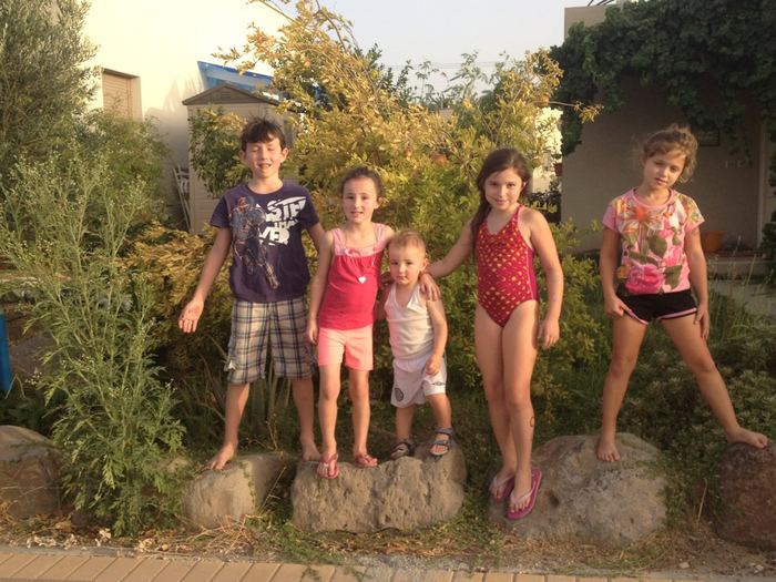 Family posing outdoors among shrubs