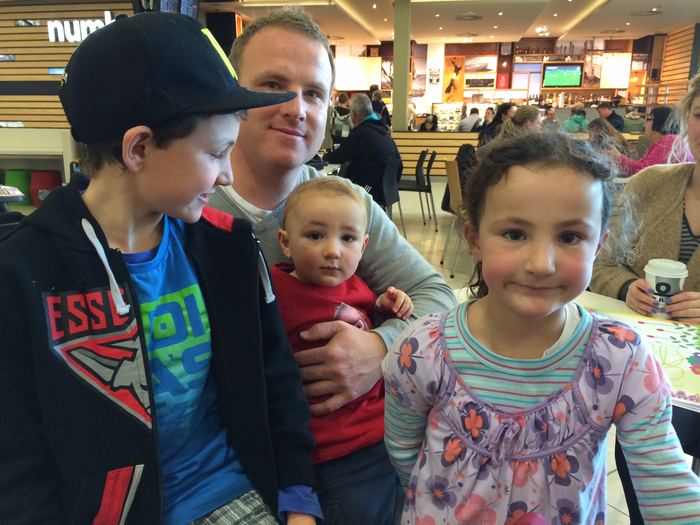 A man and three children at a shopping centre food court
