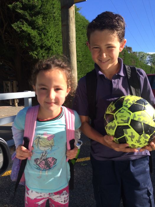 Two children in school uniform with a soccer ball