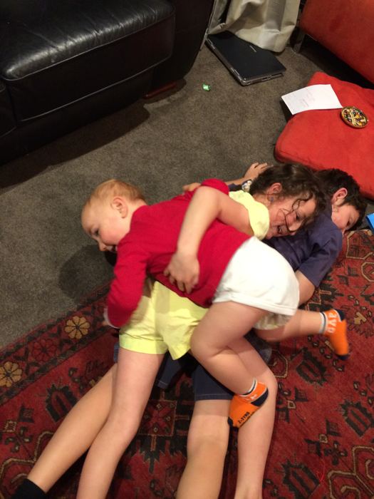 Children tumbling together on a rug