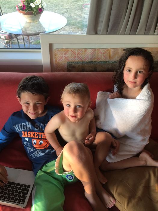 Three children sitting side by side on a couch