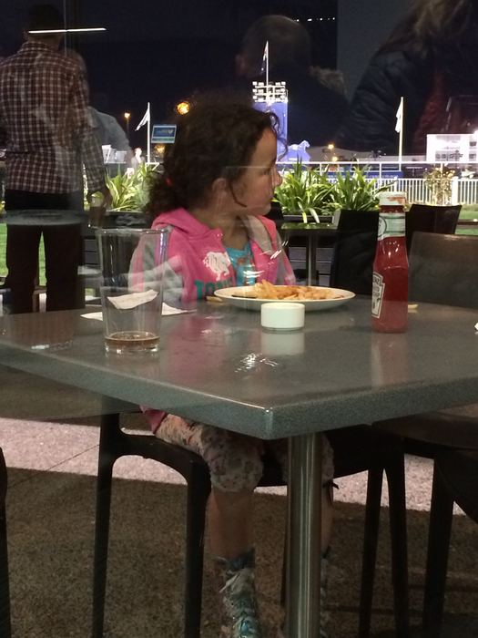 Girl at a restaurant table with city lights behind her