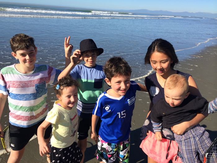 Children and an adult standing in shallow water at the beach