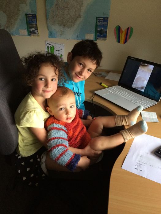 Two children and a baby at a desk with a laptop