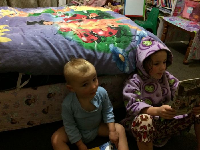 Two children playing on a bed with toys