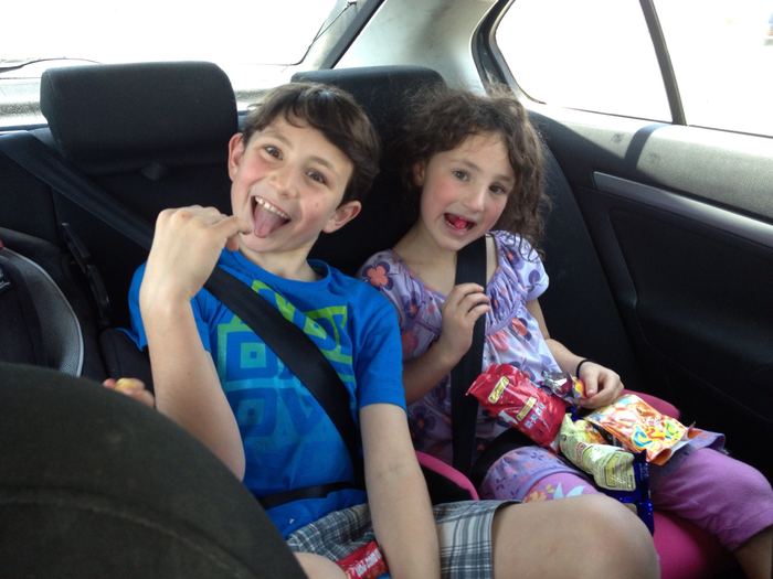 Two children pulling faces in the back seat of a car