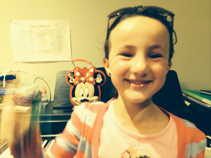 Grinning selfie at the piano beside a Minnie Mouse pencil case