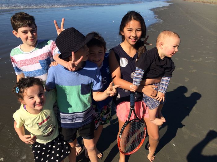 A group of children and an adult on a wide sandy beach
