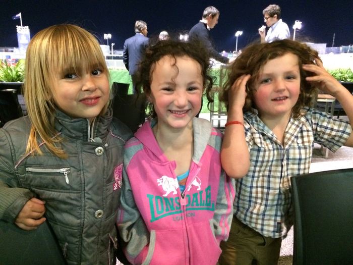 Three children smiling together at an outdoor event