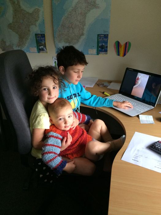 Children sharing an office chair at a desk