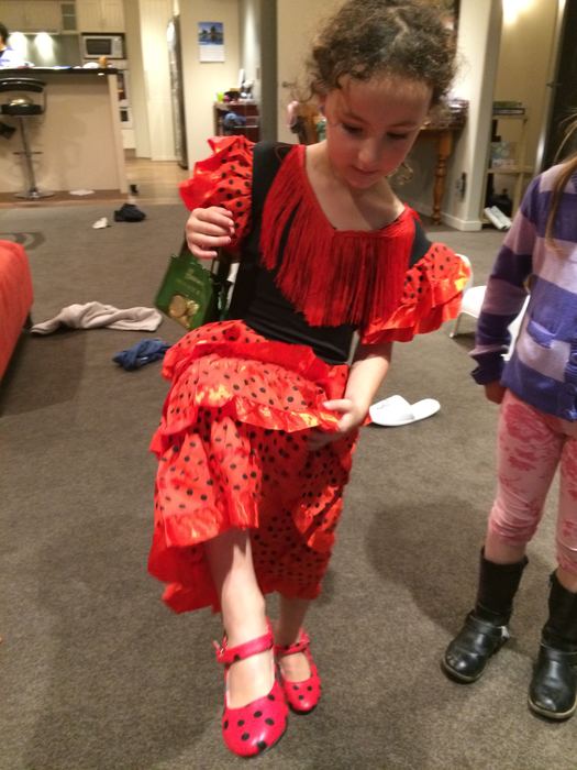 Girl in a red flamenco-style dress and red shoes indoors