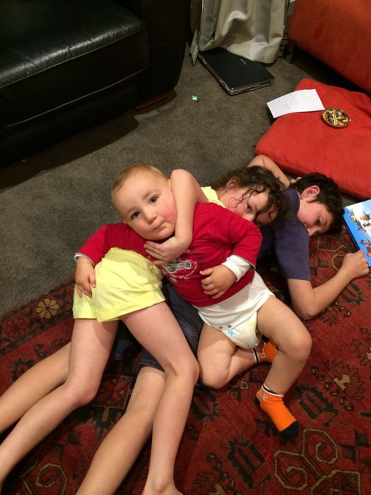 Children lying in a heap on the living room rug
