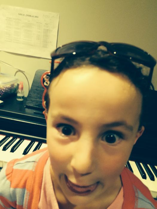 Close-up selfie of a girl with sunglasses pushed up on her head, at a piano