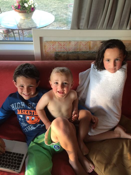 Three children sitting together on a couch with a laptop