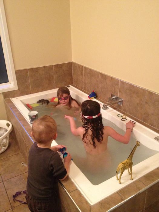 Two children playing in a bath with toys
